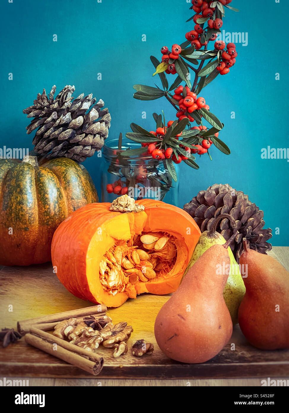 Still life of pumpkins, pine cones, pears, walnuts, spices and orange berry branches against blue background. Autumn theme. Celebration. Decor. Stock Photo
