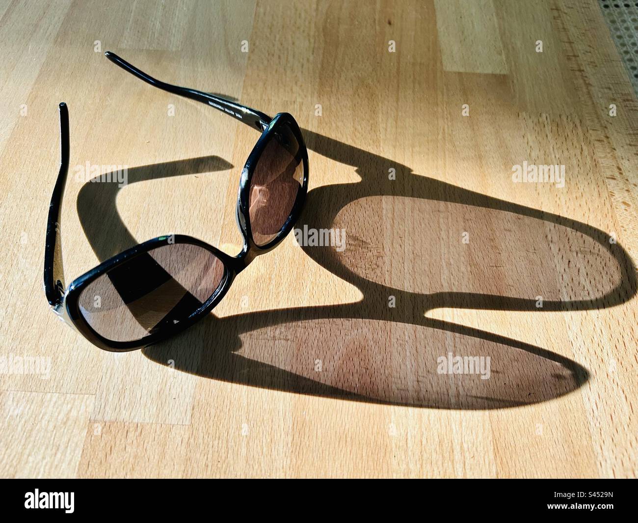 Women’s designer Sunglasses with a shadow on a table - Smartphone Captured Stock Image