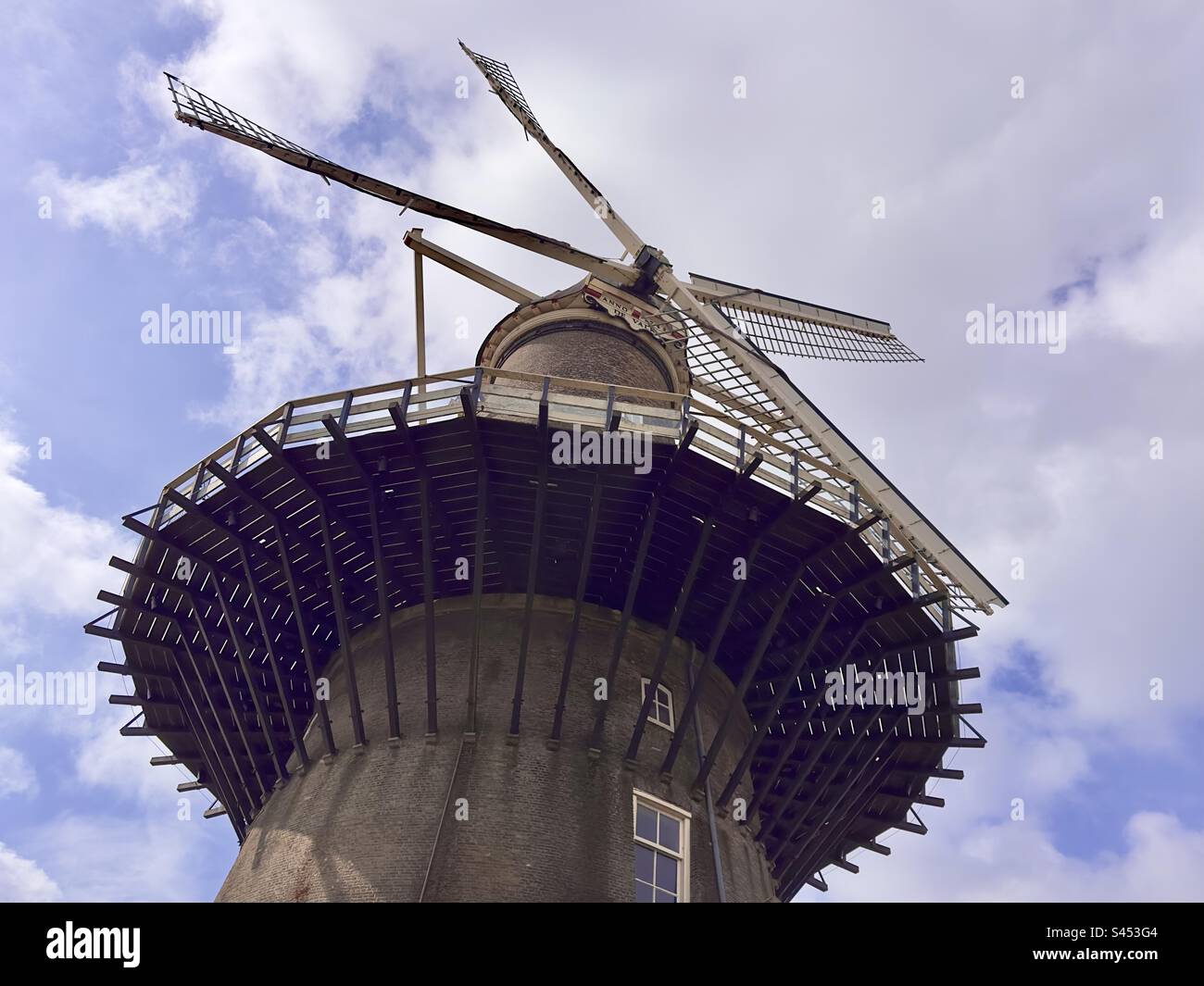 The De Valk windmill museum seen from ground level against a blue and white sky Stock Photo