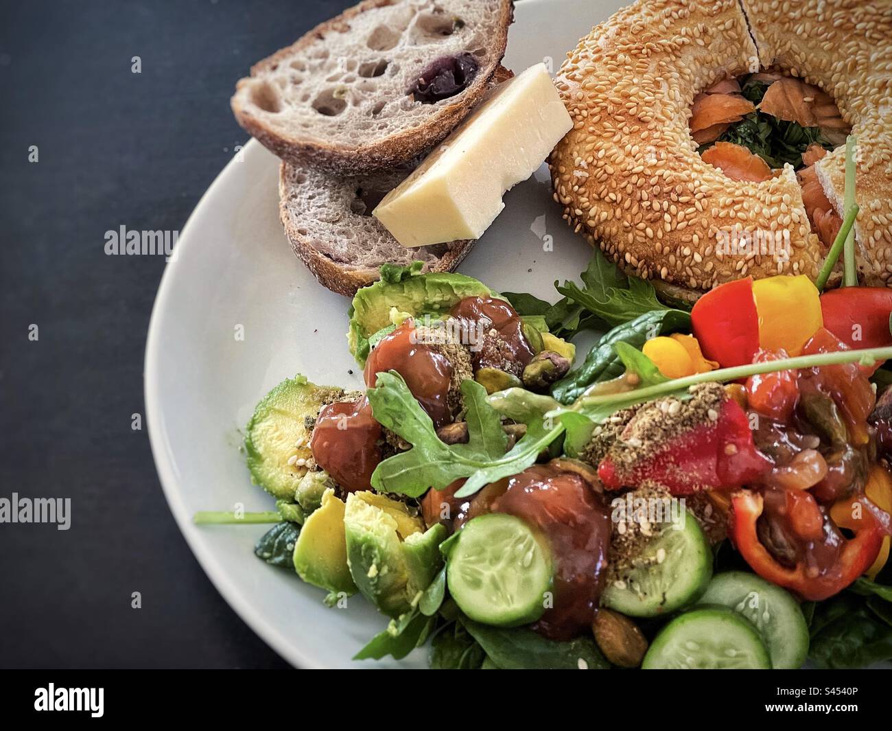 Healthy eating. Salmon bagel, olive sourdough, cheese and fresh salad with dukkah on plate on table. - Smartphone Captured Stock Image