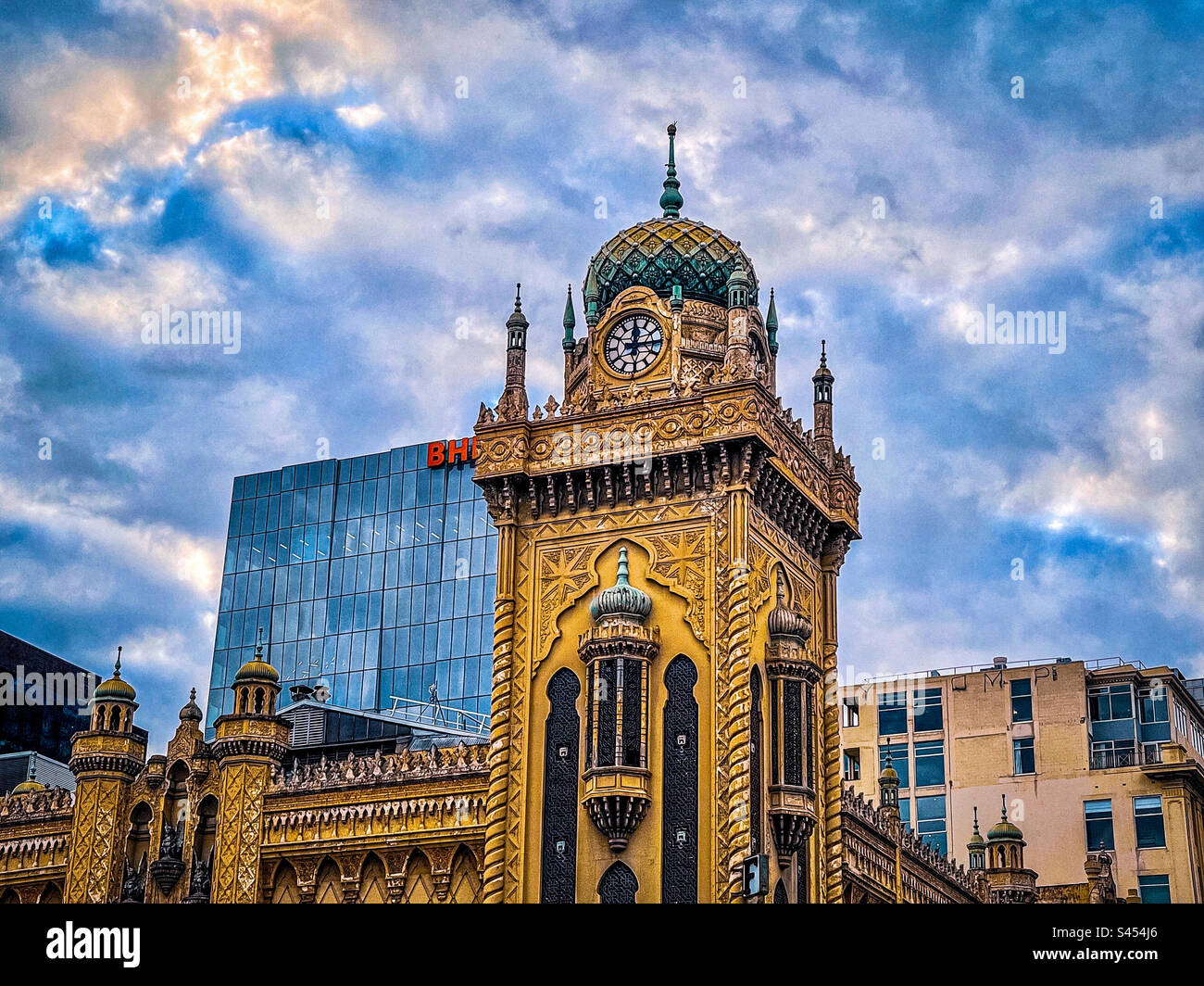 Low angle view of clock tower and minarets of The Forum theatre in Melbourne, Victoria, Australia against cloudy blue sky. Moorish revival architecture. Built in 1929. Heritage listed. Stock Photo