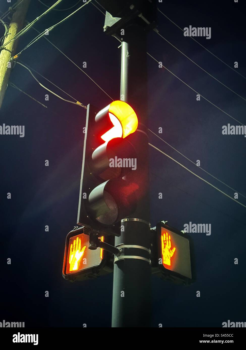 Traffic light glowing red with both crosswalk signals showing stop Stock Photo
