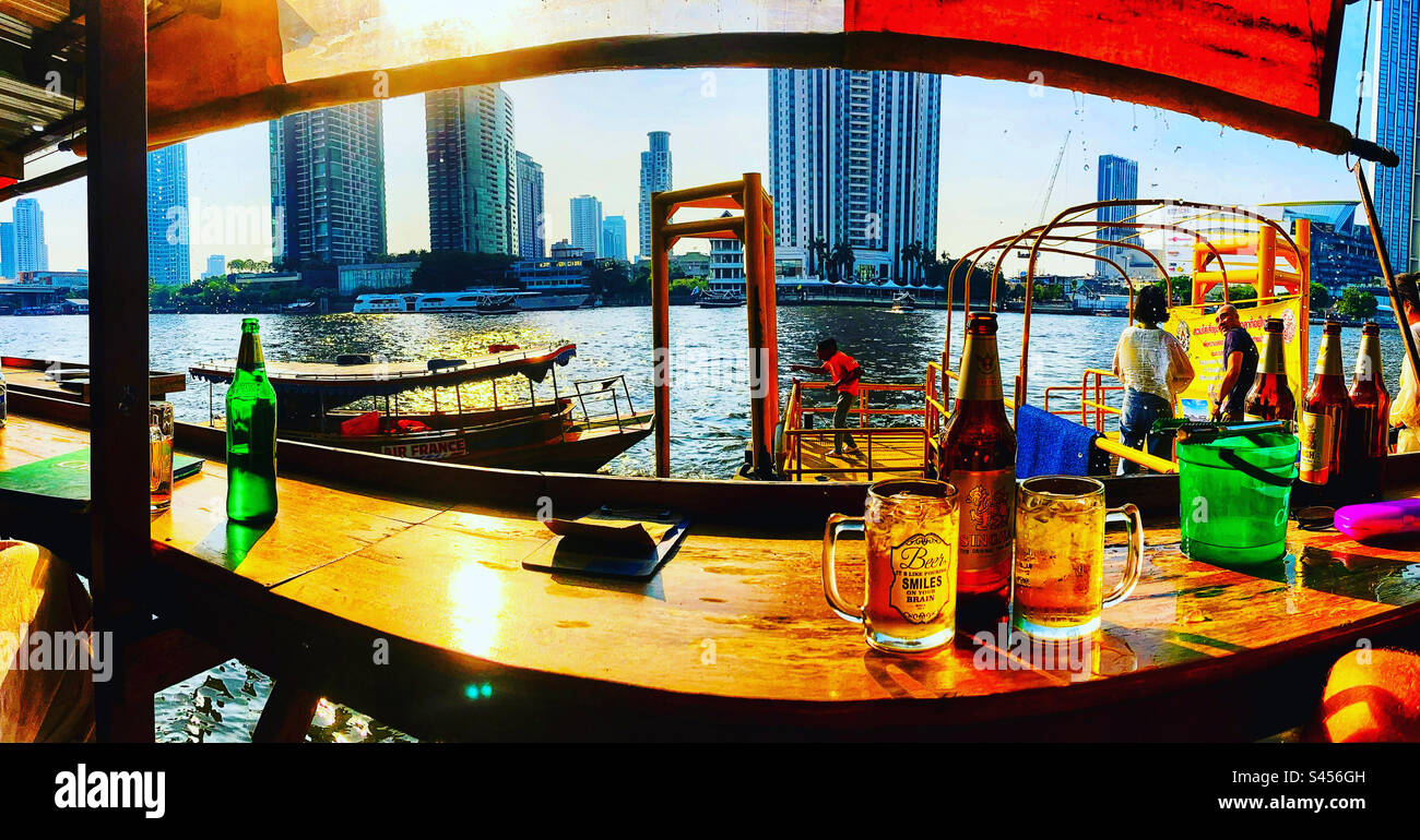 Panoramic photo of chao phraya River from bar with beer bottle and glasses in Bangkok Thailand Stock Photo