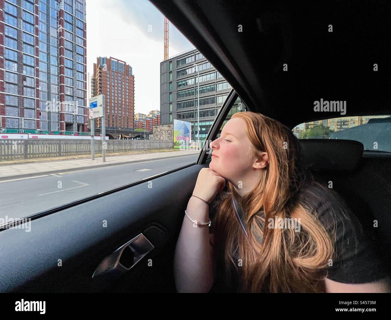 Teenager looking out of car window while travelling in Leeds City Centre - Smartphone Captured Stock Image