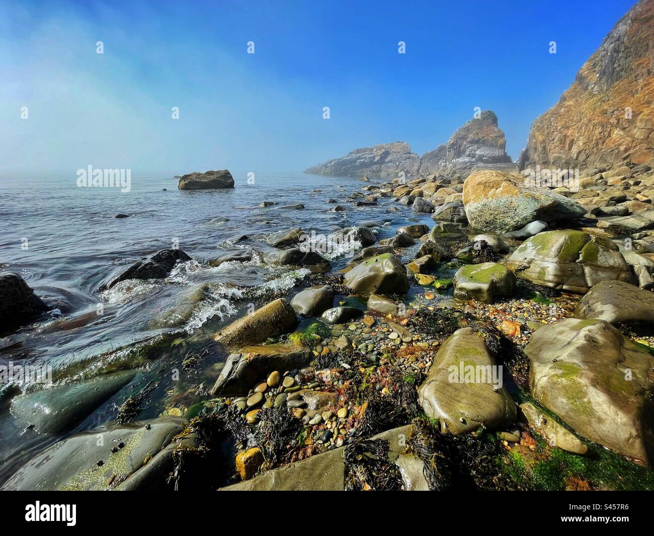 Pistyll beach, Lleyn peninsula, Gwynedd, North Wales, June, with sea mist clearing to reveal clear blue sky. - Smartphone Captured Stock Image