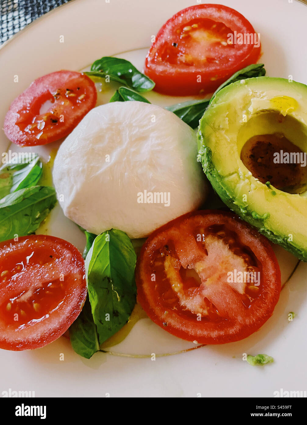 Close-up of a tricolor Italian salad of Burrata cheese, fresh basil, vine ripened tomatoes and an avocado half, 2023, USA - Smartphone Captured Stock Image