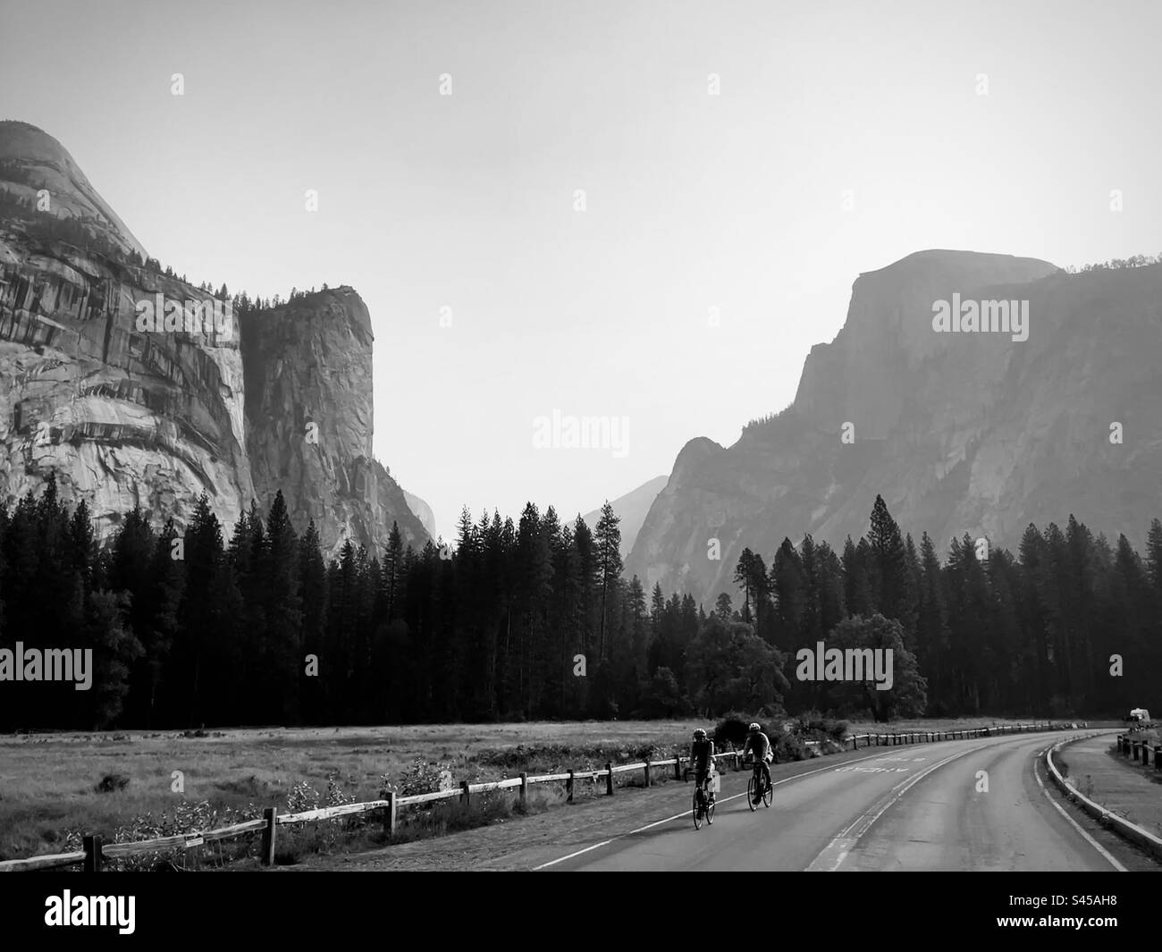 Two cyclists riding in the lower Yosemite Valley with beautiful views of Half Dome. Yosemite National Park, California USA. Stock Photo