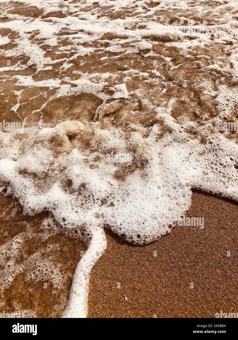 Seascape - close-up of the sea water and sea foam on the beach, sand on Costa Daurada, Spain - Smartphone Captured Stock Image Seascape - close-up of the sea water and sea foam on the beach, sand on Costa Daurada, Spain - Smartphone Captured Stock Image