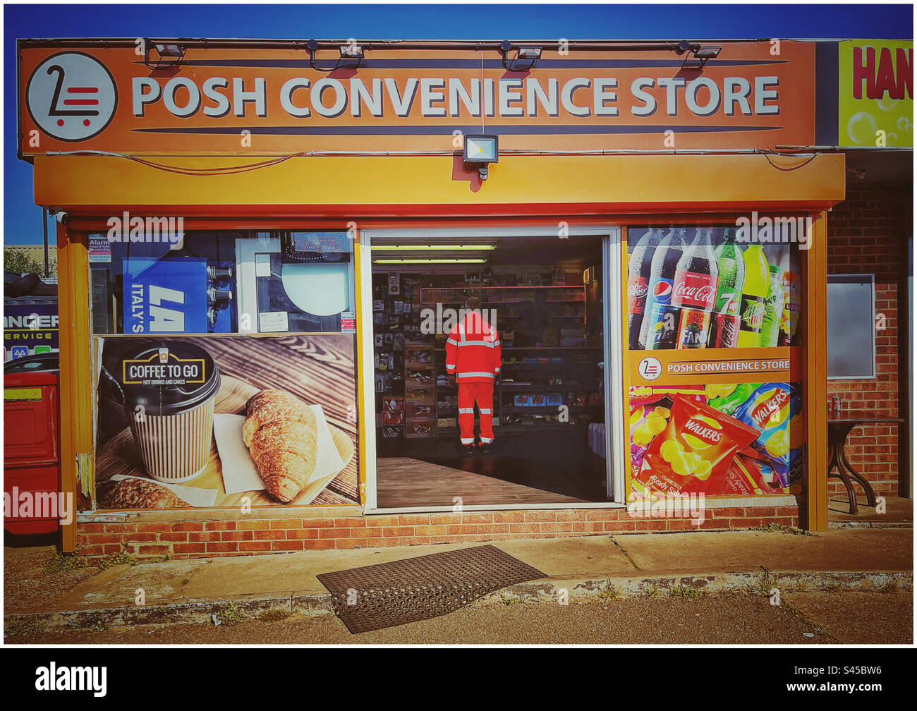 Workman wearing hi-vis clothing in doorway of convenience store Stock Photo