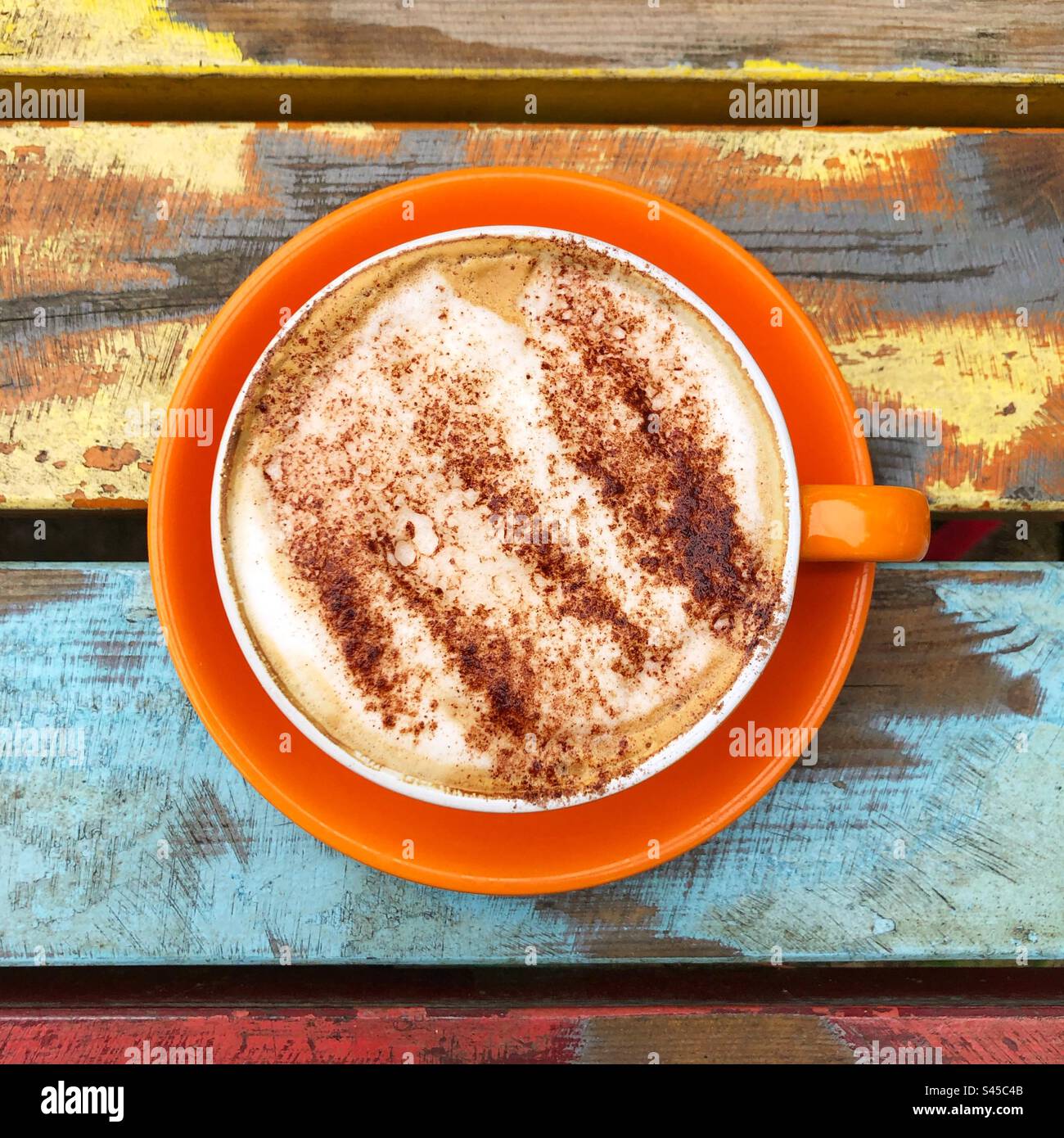 Hot drink food flat lay of a frothy cappuccino coffee with chocolate sprinkles in a colourful cup and saucer - Smartphone Captured Stock Image