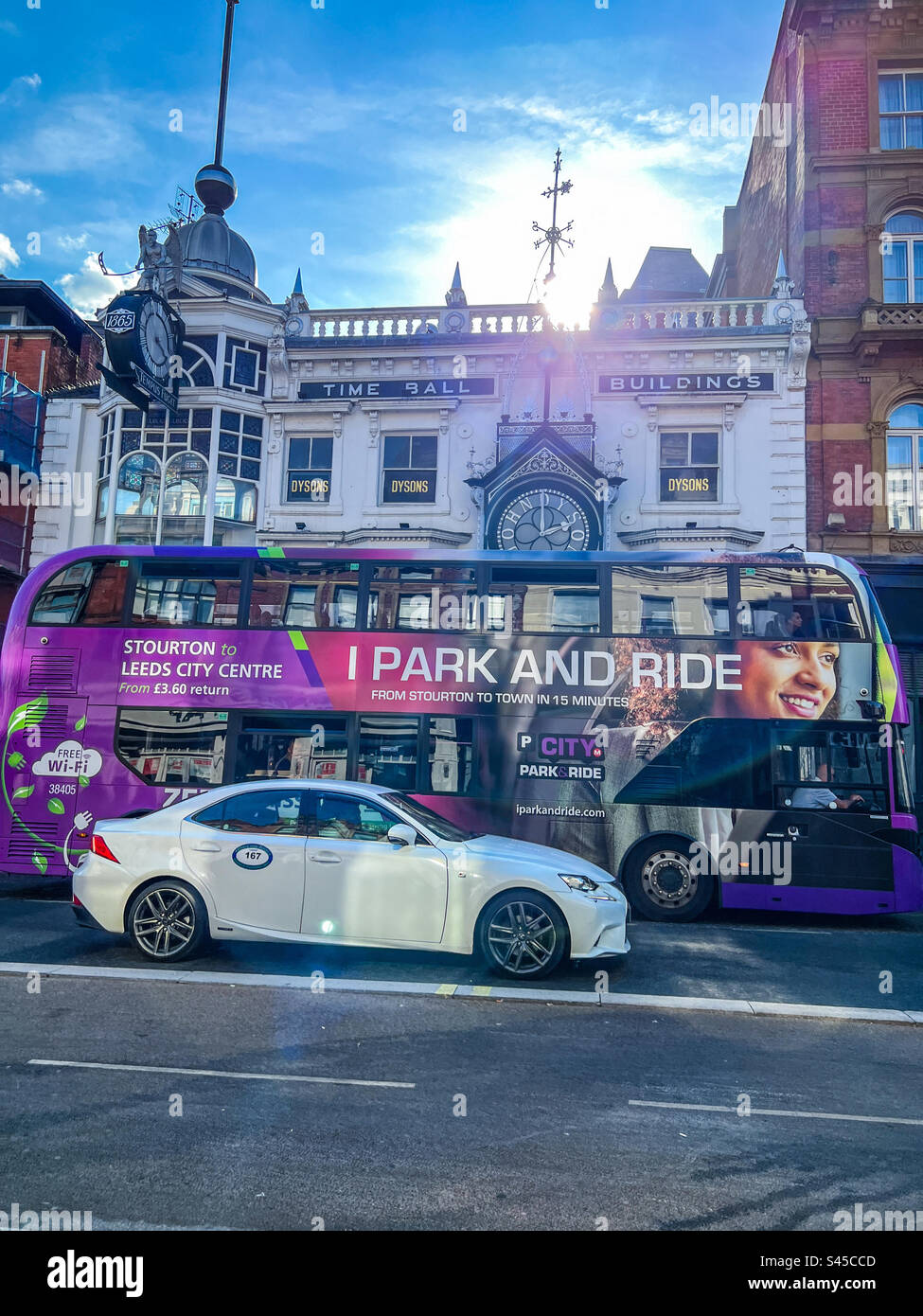 Private hire taxi and bus on Briggate next to the Time Ball buildings in Leeds City Centre Stock Photo