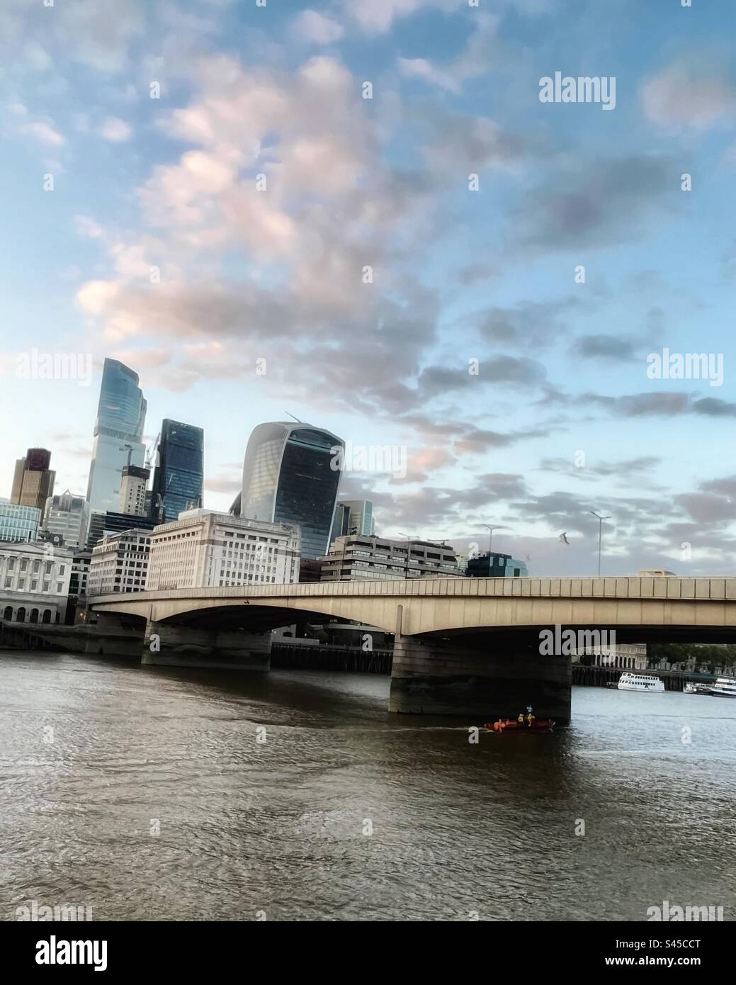 London Bridge looking from the south bank into the city of London with skyscrapers and offices. Contrasting modern architecture. River Thames with boat. - Smartphone Captured Stock Image
