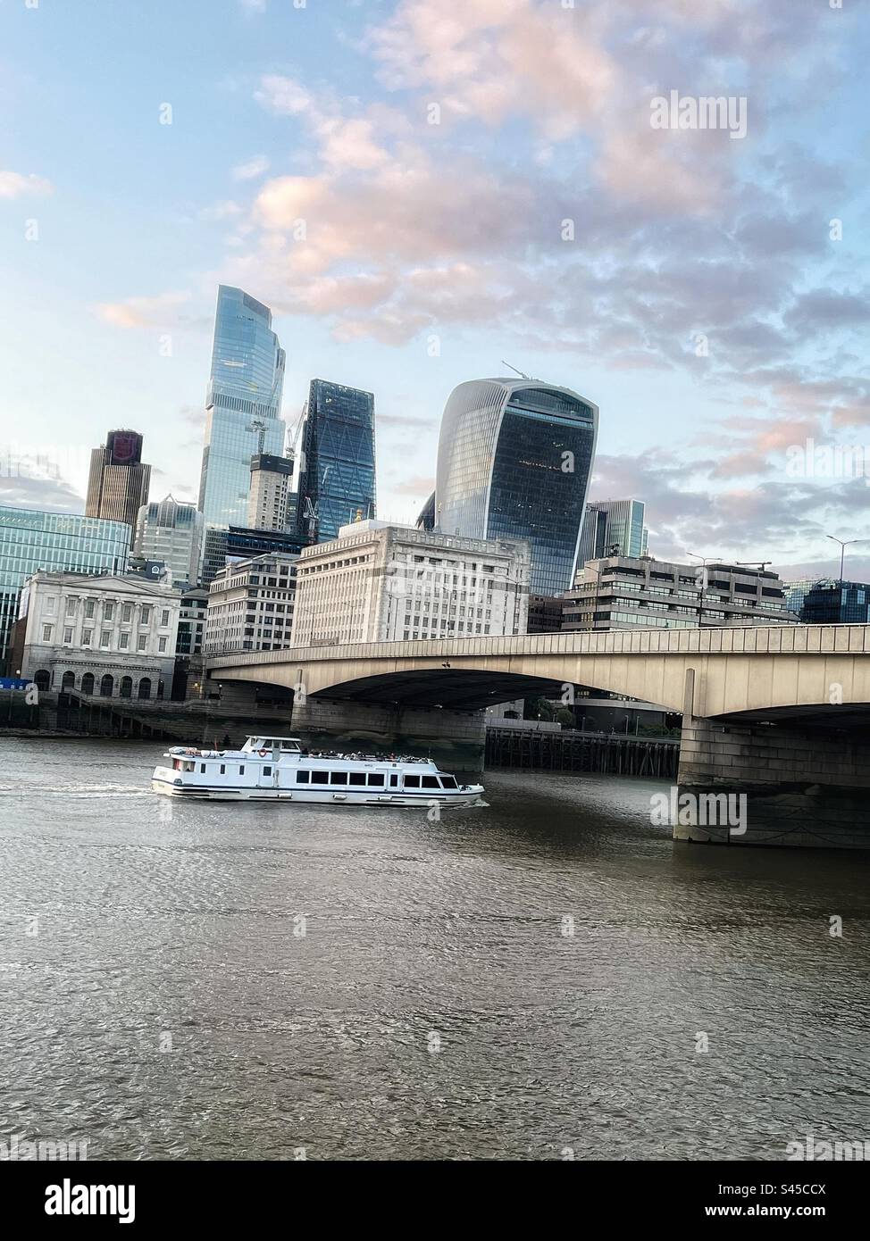Working river Thames with passenger boat approaching London Bridge view of the skyscrapers of the City - architecture is mixed - Smartphone Captured Stock Image