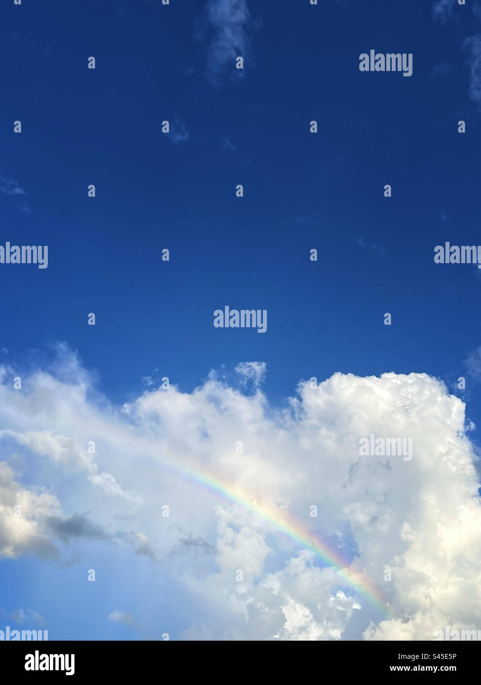 Rainbow in clouds and blue sky - Smartphone Captured Stock Image