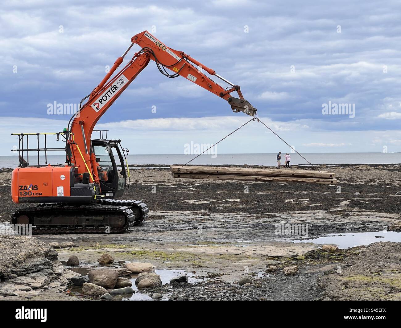 Tiny people hitch a lift on heavy plant Stock Photo