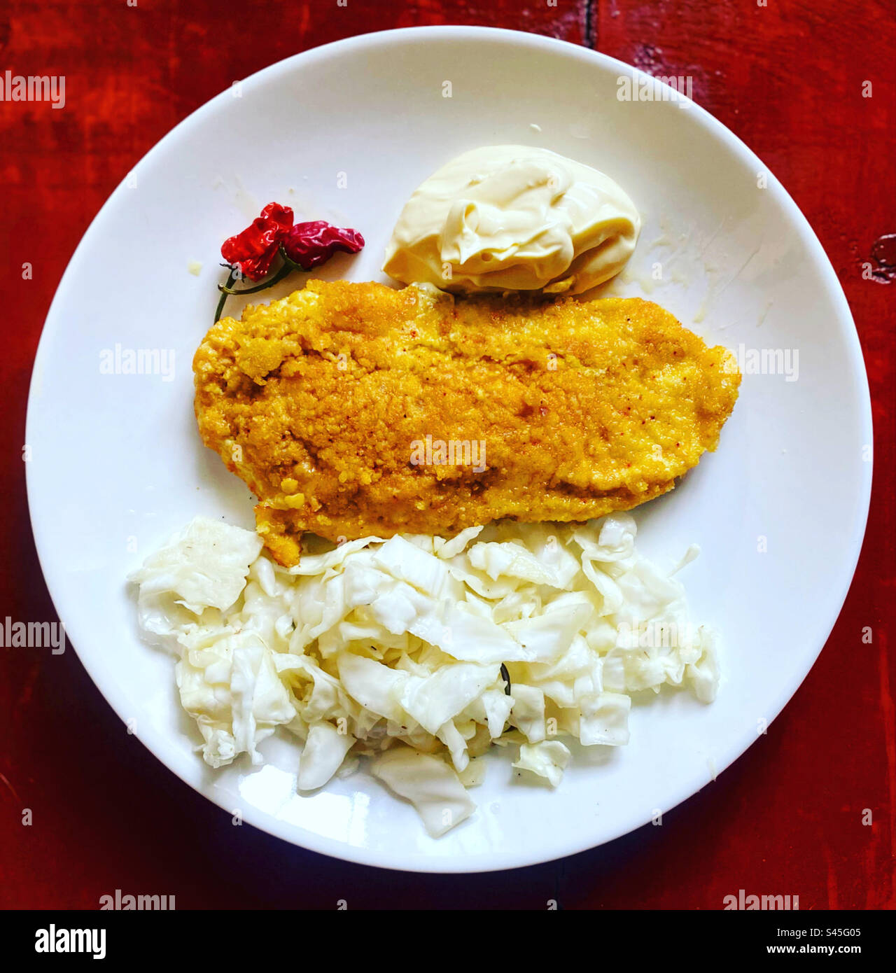 Breaded chicken with pickled cabbage, red hot chilli peppers and mayonnaise in a plate in Queretaro, Mexico - Smartphone Captured Stock Image