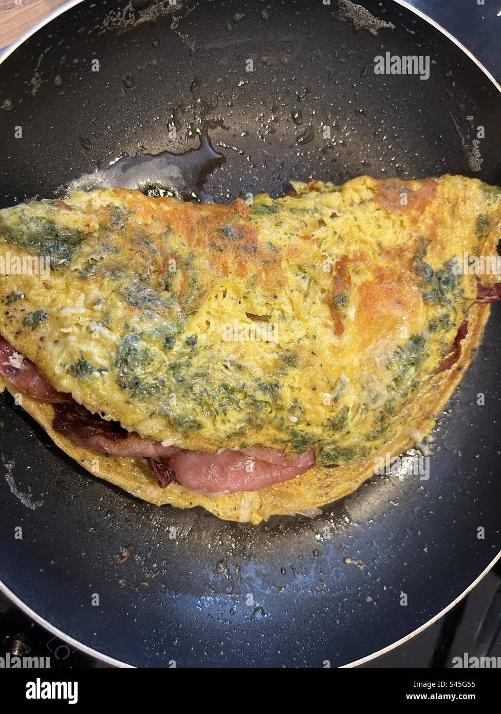 Omelette with herbs and cheese, stuffed with crispy bacon. Stock Photo