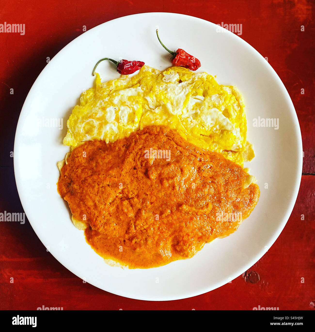 Eggs omelette and tomato sauce with red hot chilli peppers for breakfast in Queretaro, Mexico - Smartphone Captured Stock Image