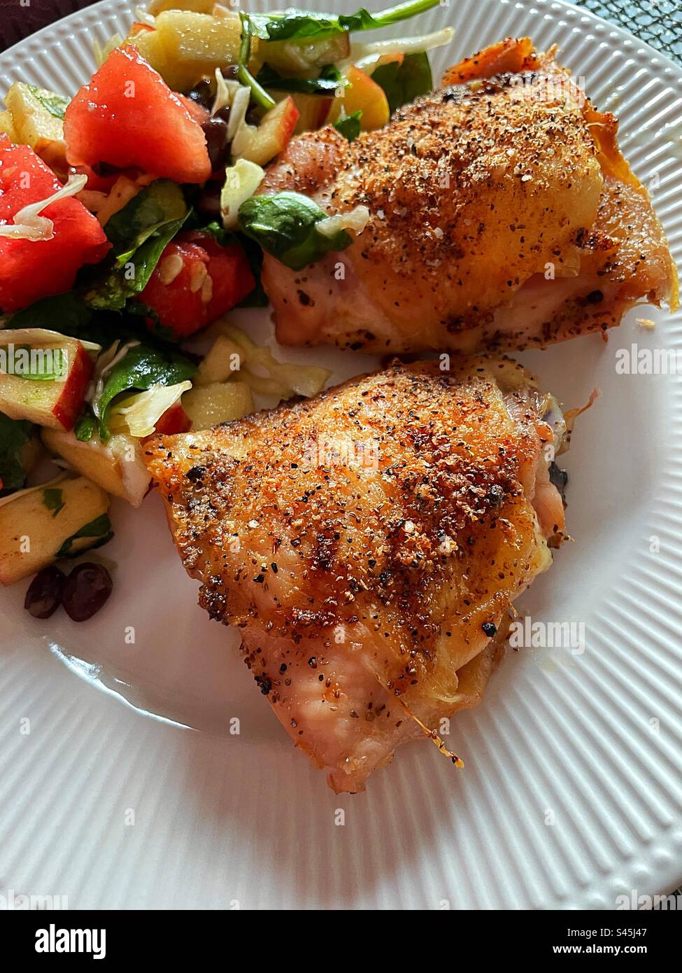 Close-up of a festive summer meal of crispy baked chicken thighs in a watermelon-based salad, 2023, USA Stock Photo