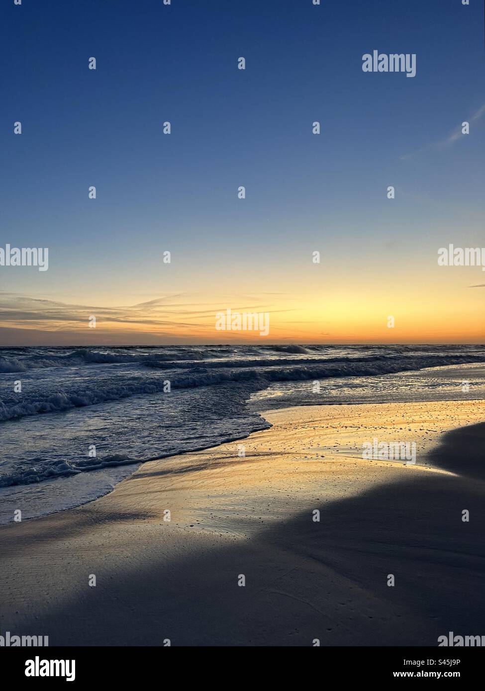 Gulf of Mexico Emerald Coast Florida blue hour sunset with reflections of colors onto the sand - Smartphone Captured Stock Image