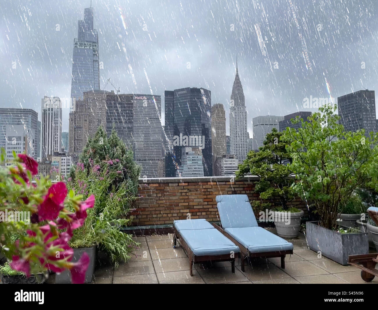 A luxury co-op roof deck has a view of Midtown skyscrapers during a summer thunderstorm, 2023, New York City, USA - Smartphone Captured Stock Image