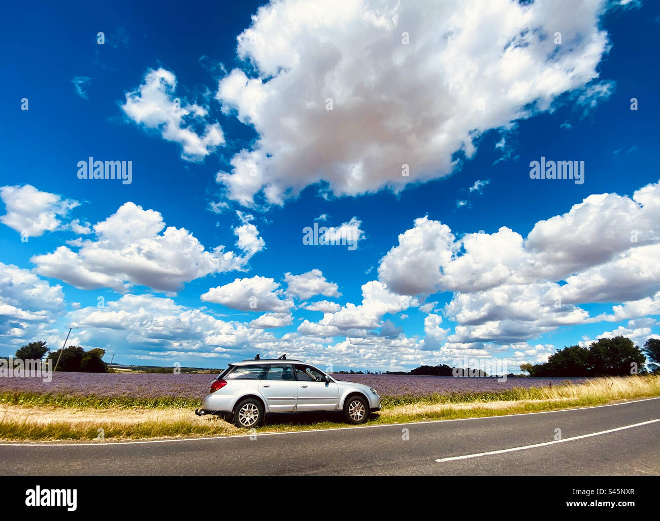 A silver estate car is parked next to the road by an agricultural field on a beautiful day in Suffolk England - Smartphone Captured Stock Image