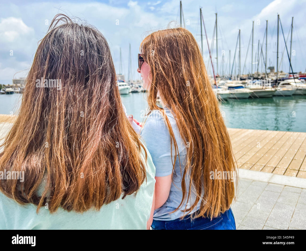 Two young women walking on harbour in Alicante in Spain Stock Photo