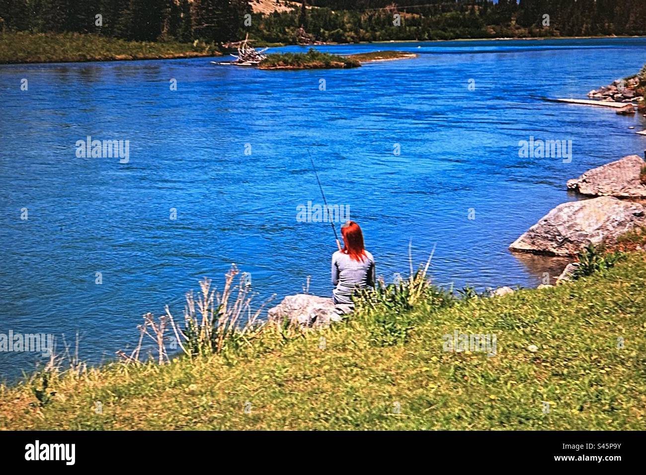 Woman fishing in the river, Bow River, red head, solitude - Smartphone Captured Stock Image
