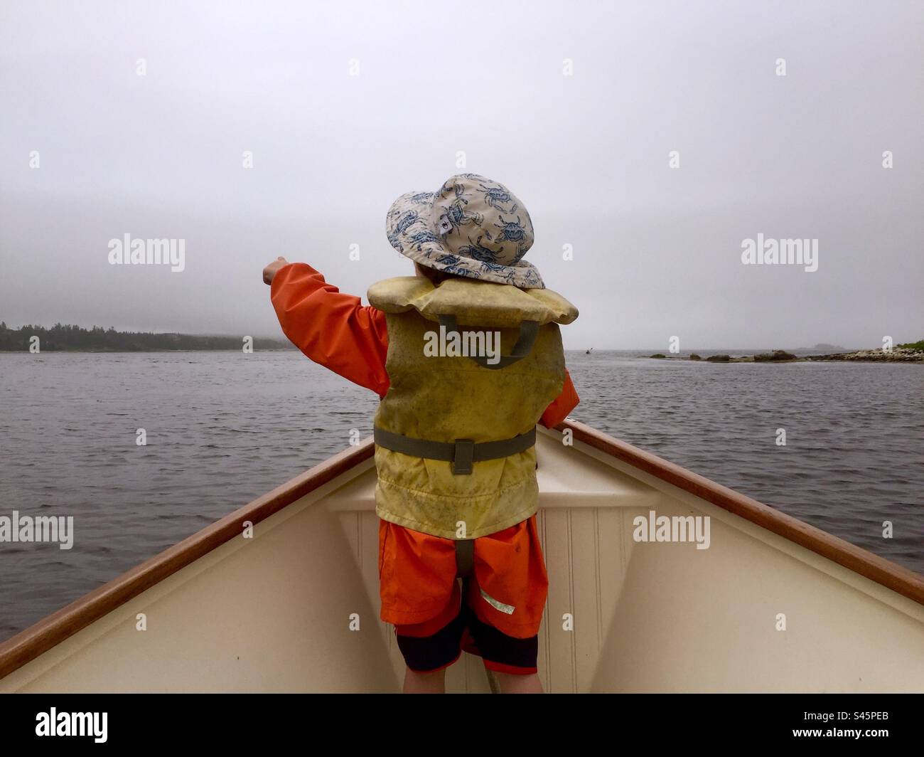That way. A toddler in the boat’s bow points SE. Nova Scotia, Canada. - Smartphone Captured Stock Image