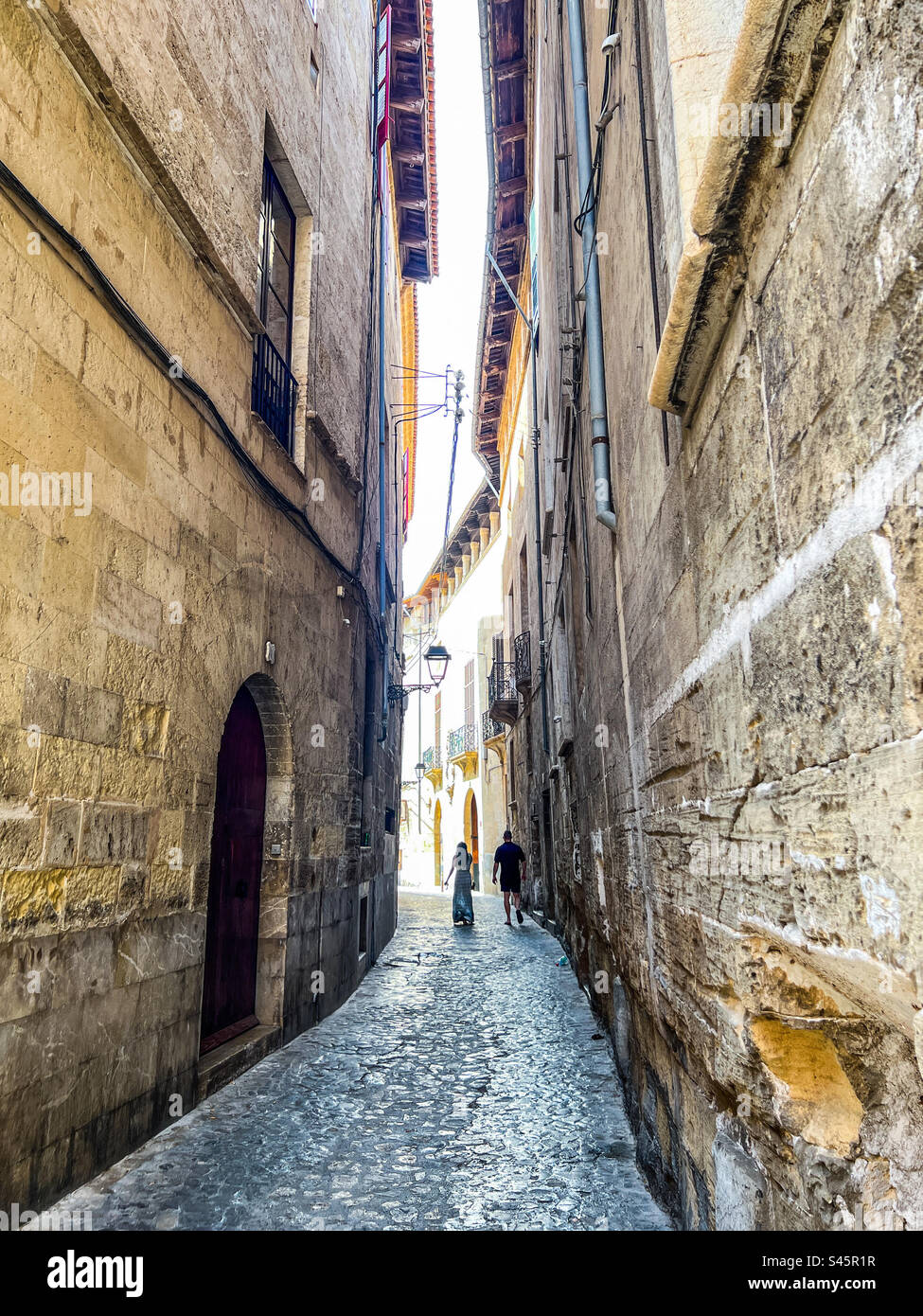 Young couple romantically walking down an ancient street in Palma Mallorca in the Balearic Islands - Smartphone Captured Stock Image