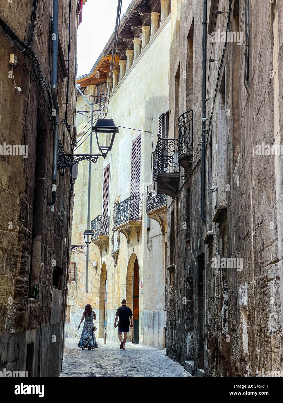 Young couple walking down an ancient street in Palma Mallorca in the Balearic Islands - Smartphone Captured Stock Image