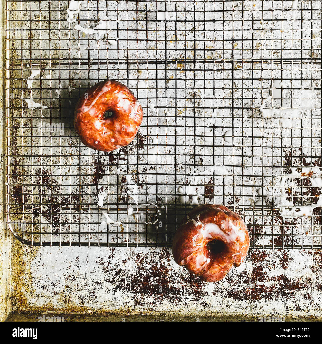 Fresh glazed donuts cooling on a wire rack. Stock Photo