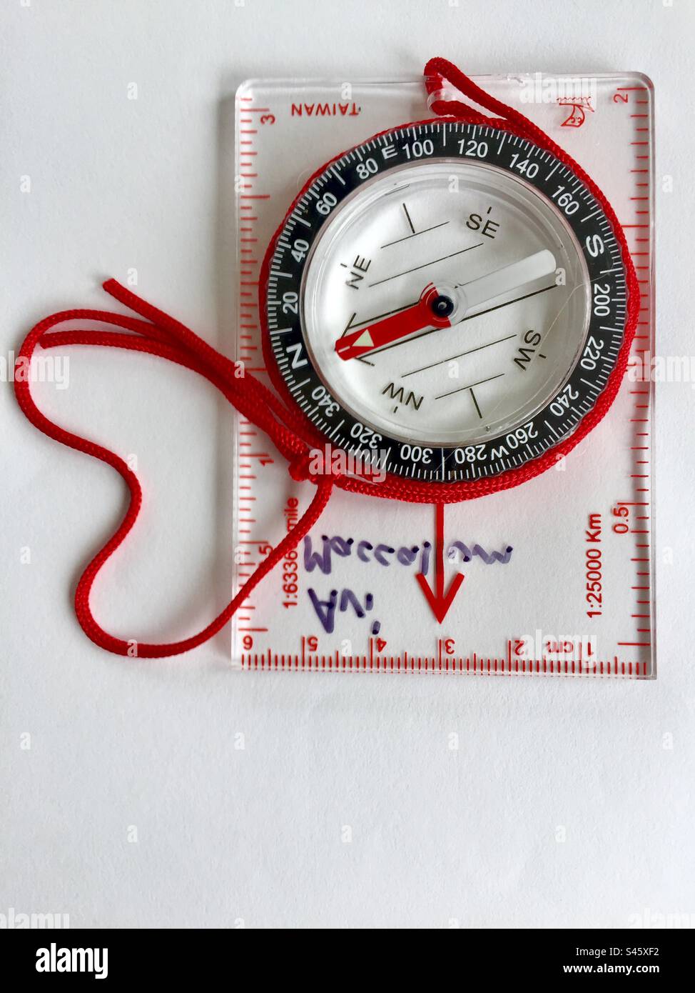 The North in my heart. A compass with a red string points north. White backdrop. - Smartphone Captured Stock Image