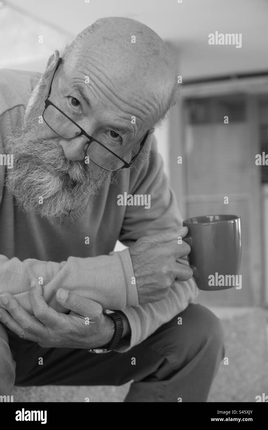 Poor old man drinking coffee Stock Photo