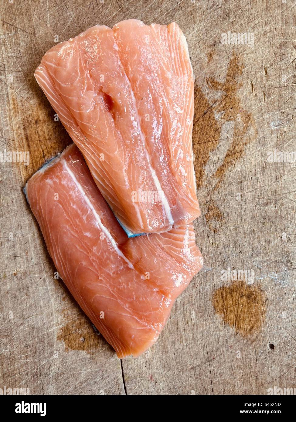 Fresh salmon tails on a wet chopping board. - Smartphone Captured Stock Image