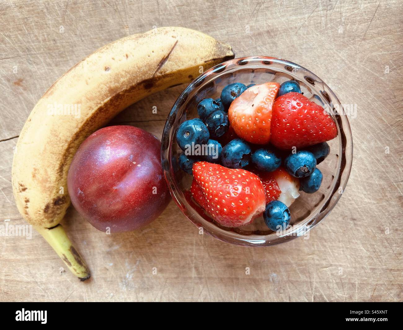 Colourful,banana,nectarine, strawberries and blueberries on a chopping board. Stock Photo