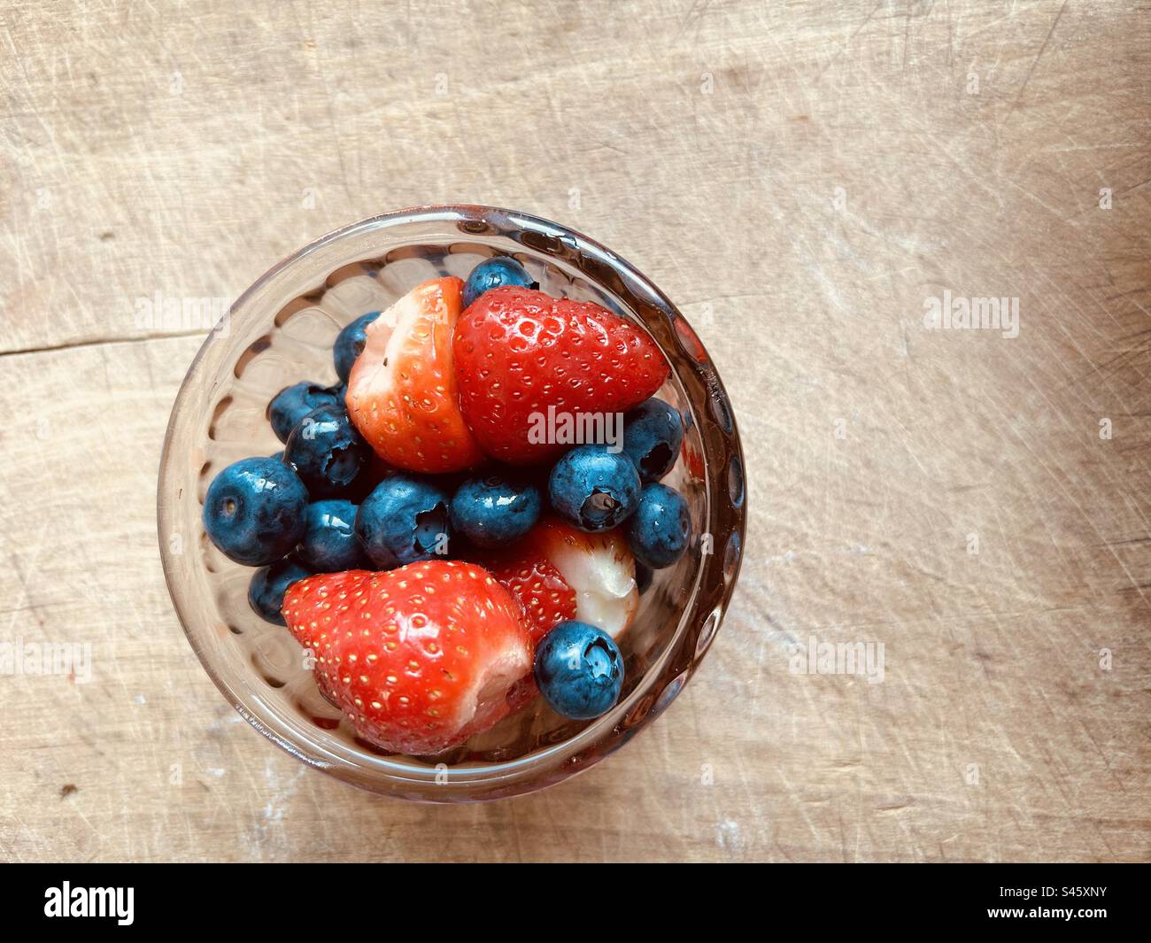 Bright and colourful fresh summer blueberries  and strawberries in a small glass bowl. - Smartphone Captured Stock Image