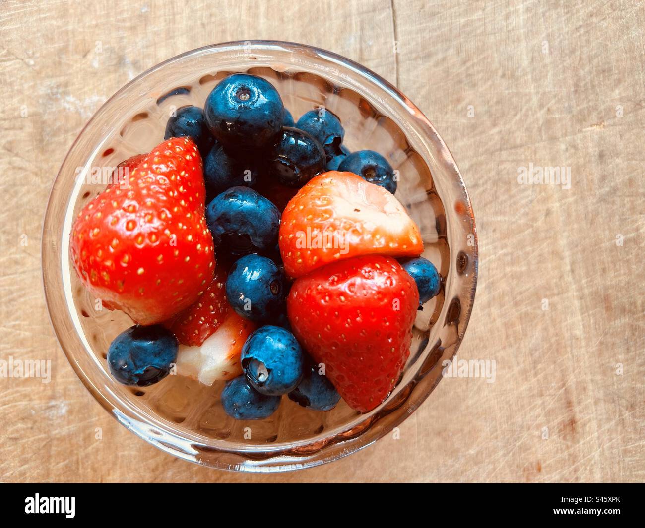 Close-up colourful fresh summer blueberries  and strawberries in a small glass bowl. - Smartphone Captured Stock Image