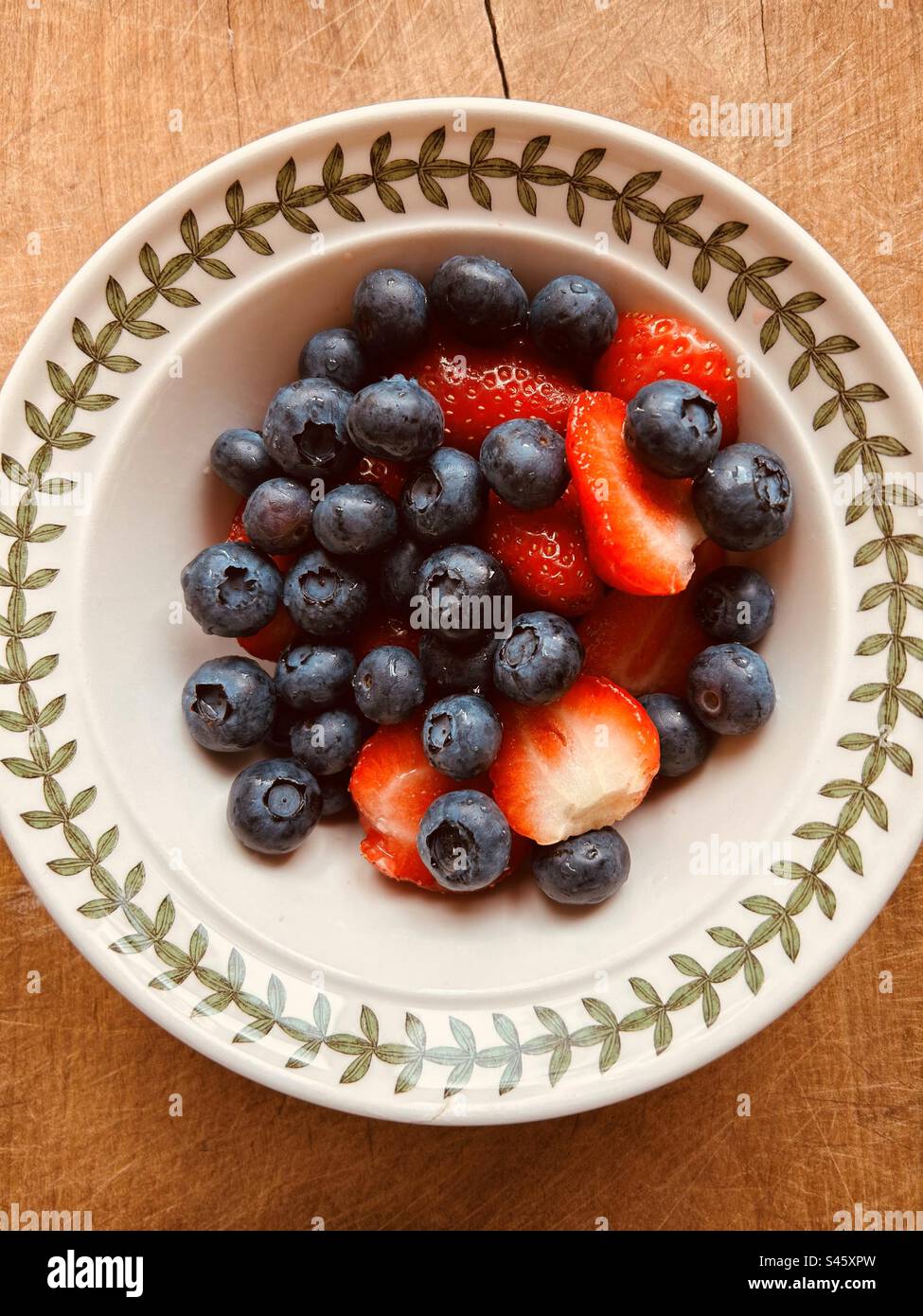 Colourful fresh summer blueberries  and strawberries in a ceramic breakfast bowl. Stock Photo