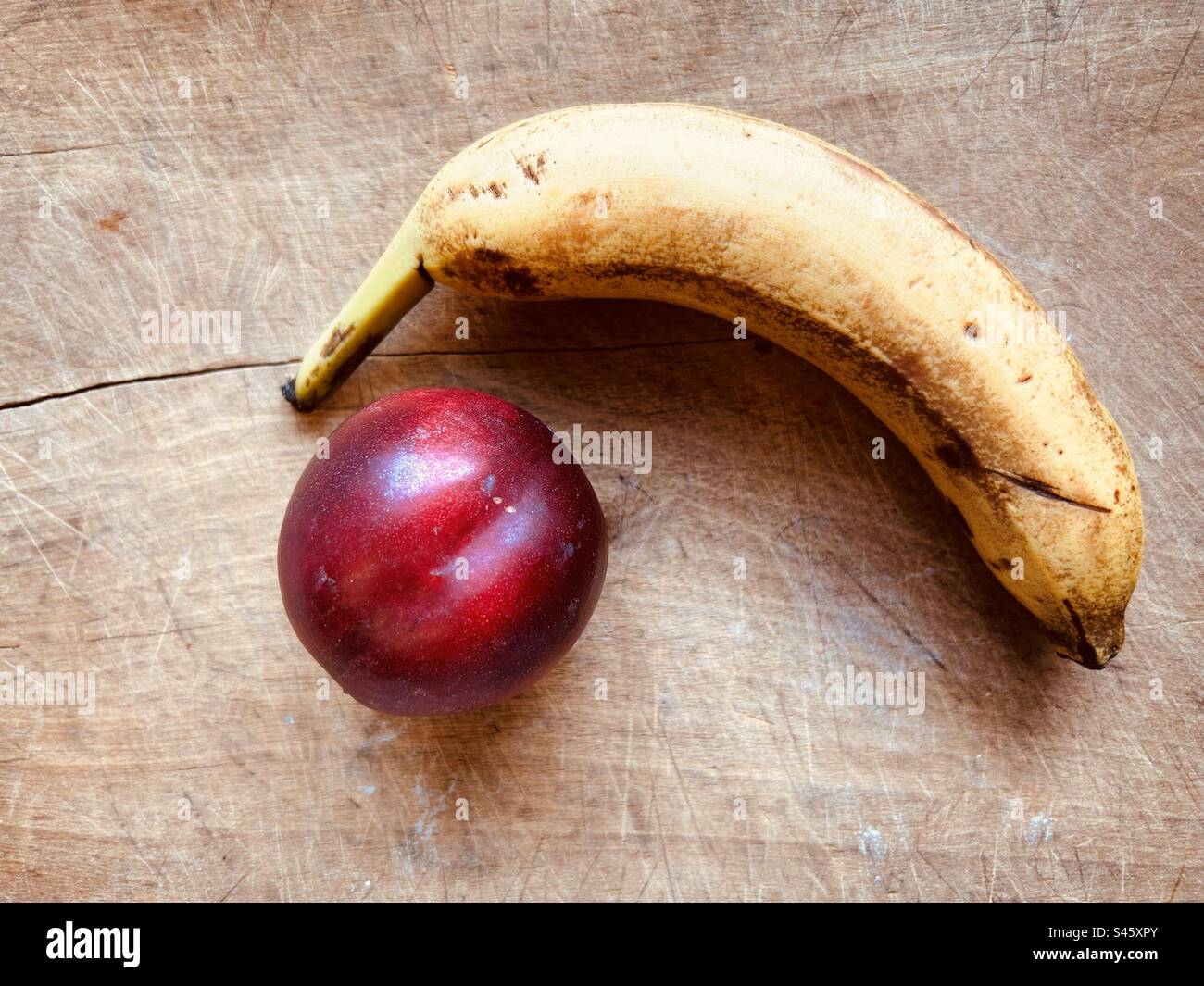 Banana and nectarine on a wooden chopping board. Fresh fruit ready to eat. Stock Photo