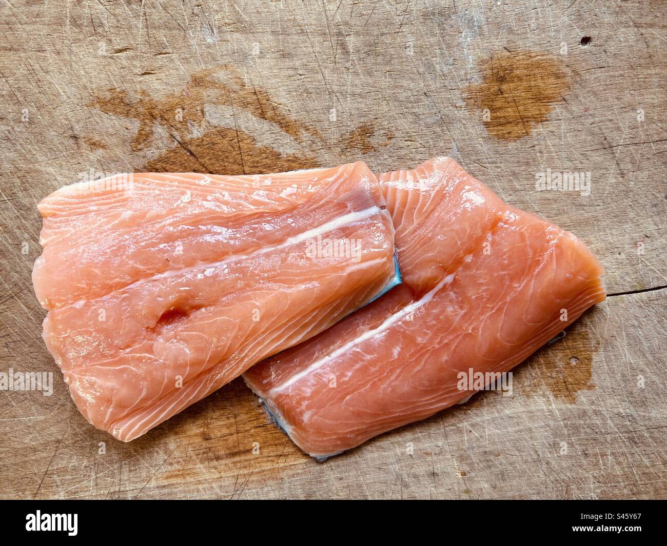 Fresh salmon tails on a wet chopping board. Ready to cook. - Smartphone Captured Stock Image