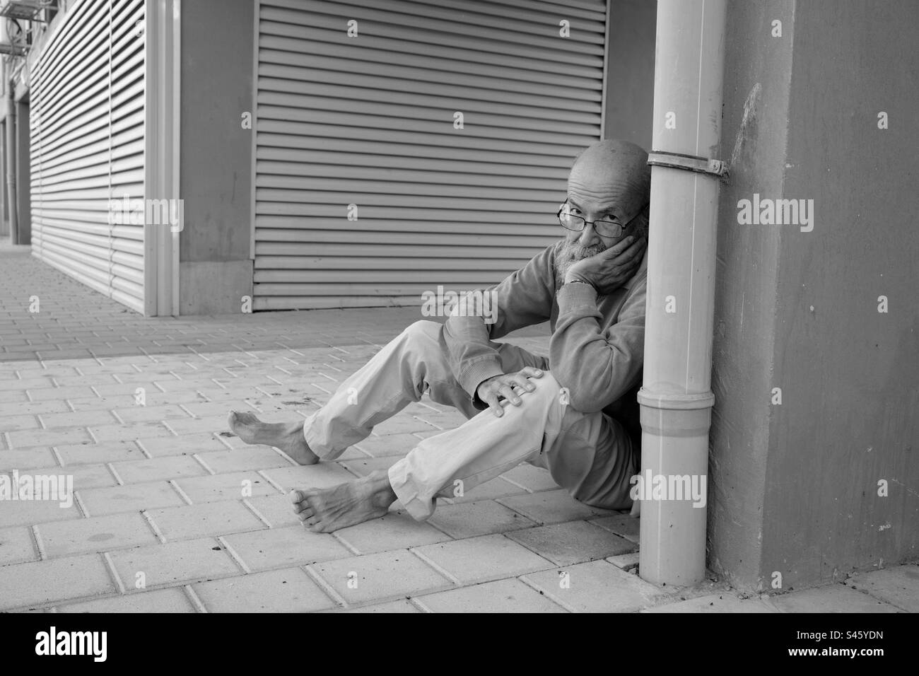 Poor old man in town BW Stock Photo