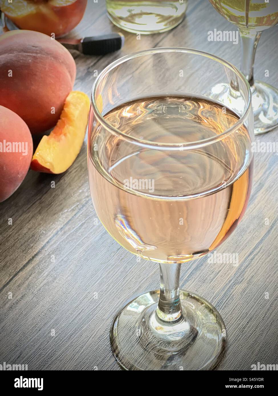 Peach wine in a clear wine glass on a wooden table Stock Photo
