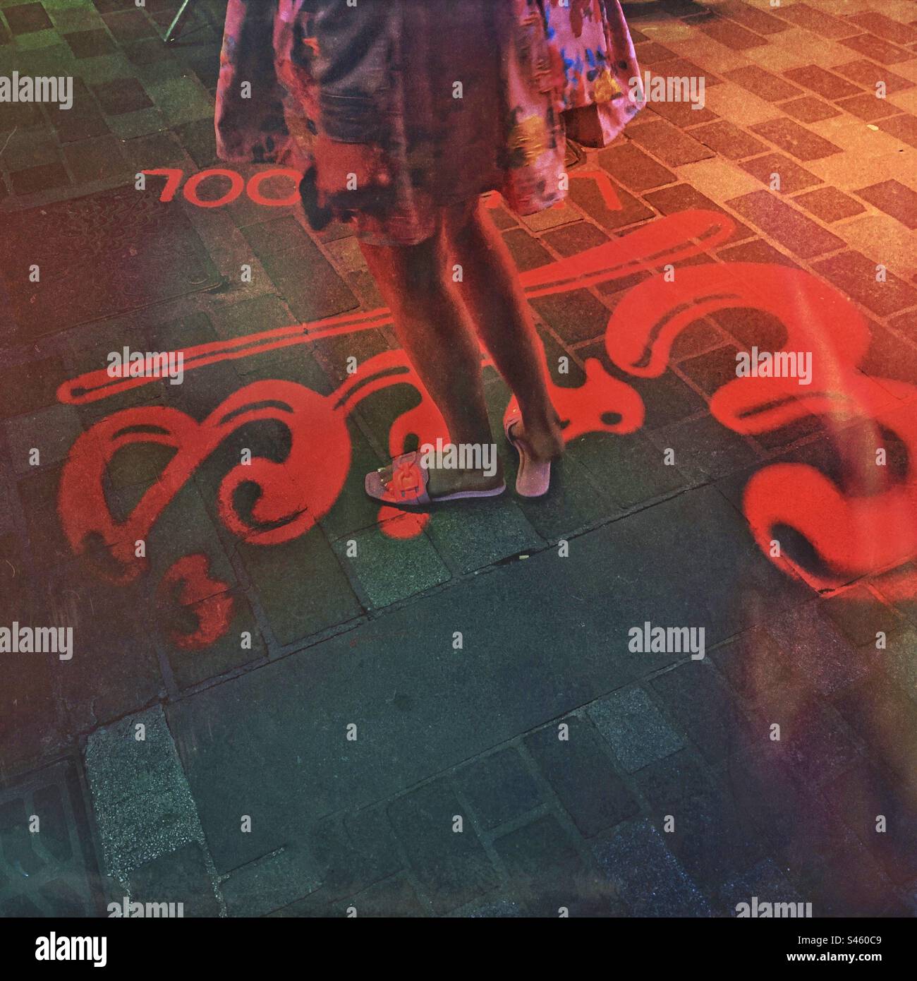 A tourist standing on a coloured digital projection display in the music tourist attraction Mathew Street outside Eric’s Club in Liverpool England UK - music tourism - Smartphone Captured Stock Image