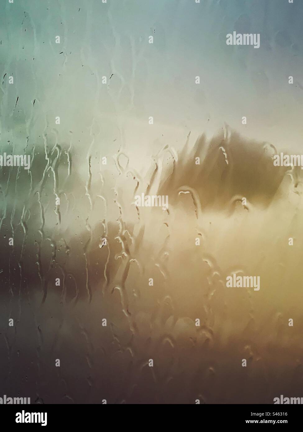 Rain on a glass window with wet weather rain clouds and sky background- raining cloud sky backdrop - Smartphone Captured Stock Image