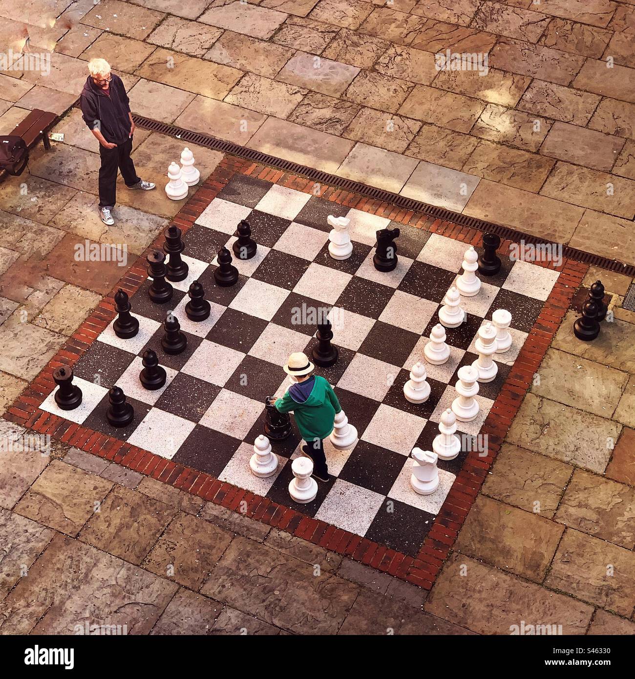 Playing outdoor chess on a large giant chessboard - Smartphone Captured Stock Image