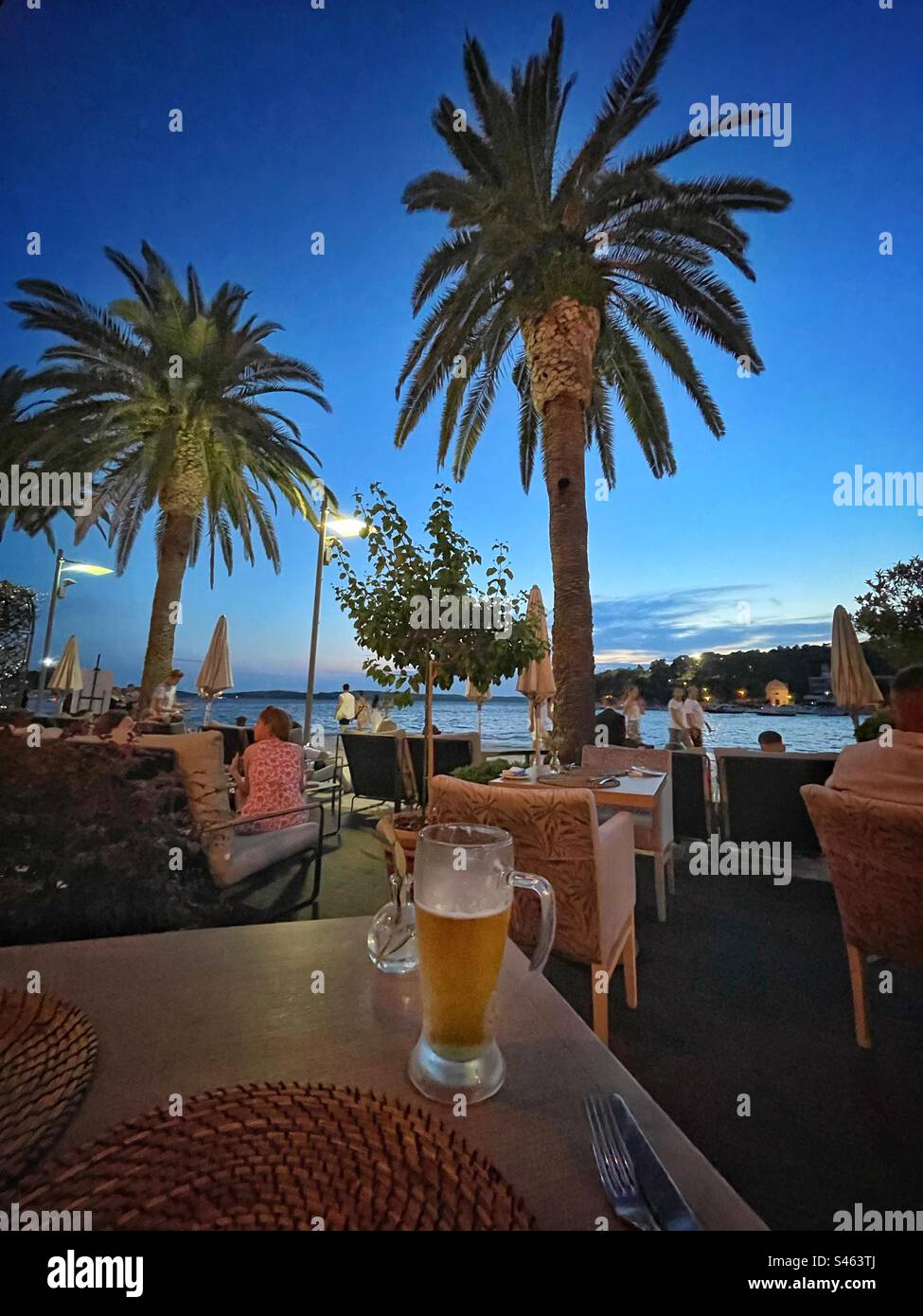 Enjoying a drink at a waterfront restaurant in Hvar town, Hvar, Croatia, August. Stock Photo