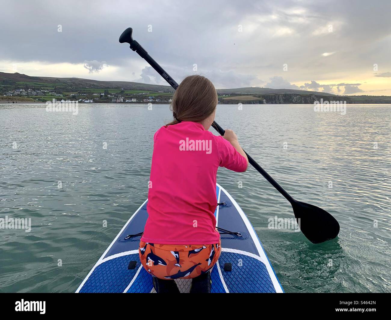 Girl in pink top paddle boarding on knees - Smartphone Captured Stock Image