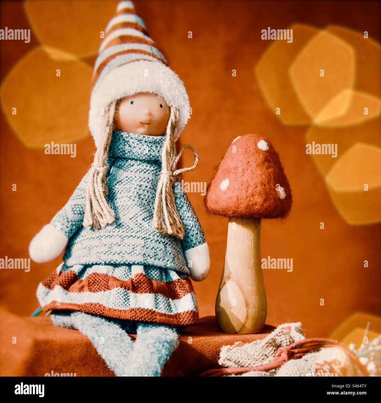 Christmasy doll sits with pinecones, present sack & mushroom in red - Smartphone Captured Stock Image
