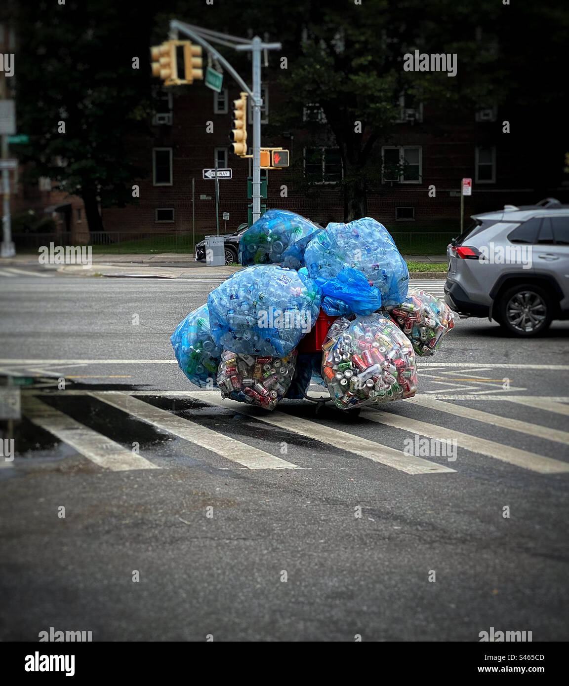 Cart with bags of recyclables being wheeled across a city street Stock Photo